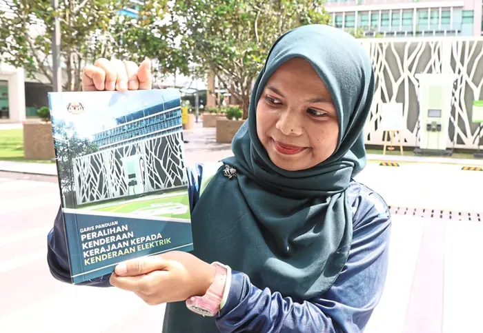 Way to go: Nurhani Mat Razaki, an analyst with the Malaysian Green Technology and Climate Change Corporation, showing the EV guidebook after the launch by Nik Nazmi in Putrajaya. — ART CHEN/ The Star