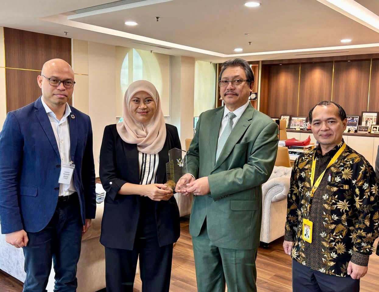 Elina (second left) hands over Dr Hazland (second right) a momento after the meeting, witnessed by Azimeer (left) and Joseph.